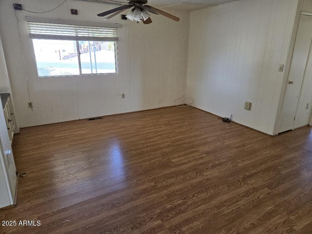 19065 North Dinero Road Sun City, AZ 85373 - Photo 13 of 37 an empty room with wooden floor and windows