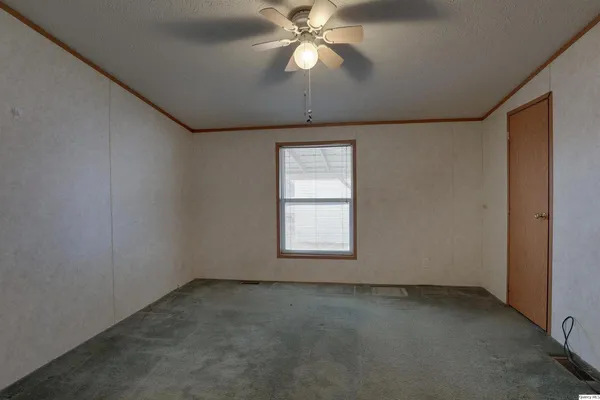 an empty room with a chandelier fan and windows