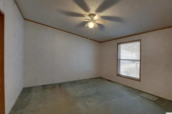 an empty room with windows and fan