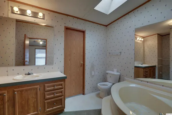 a spacious bathroom with a double vanity sink a large mirror a toilet and a bathtub