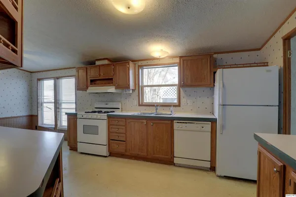a kitchen with granite countertop a refrigerator stove top oven and sink