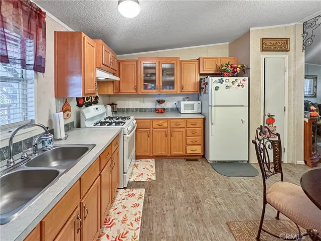 a kitchen with a refrigerator a sink dishwasher and a stove with wooden cabinets