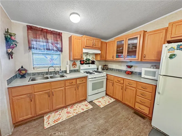 a kitchen with granite countertop a sink cabinets stainless steel appliances and a window