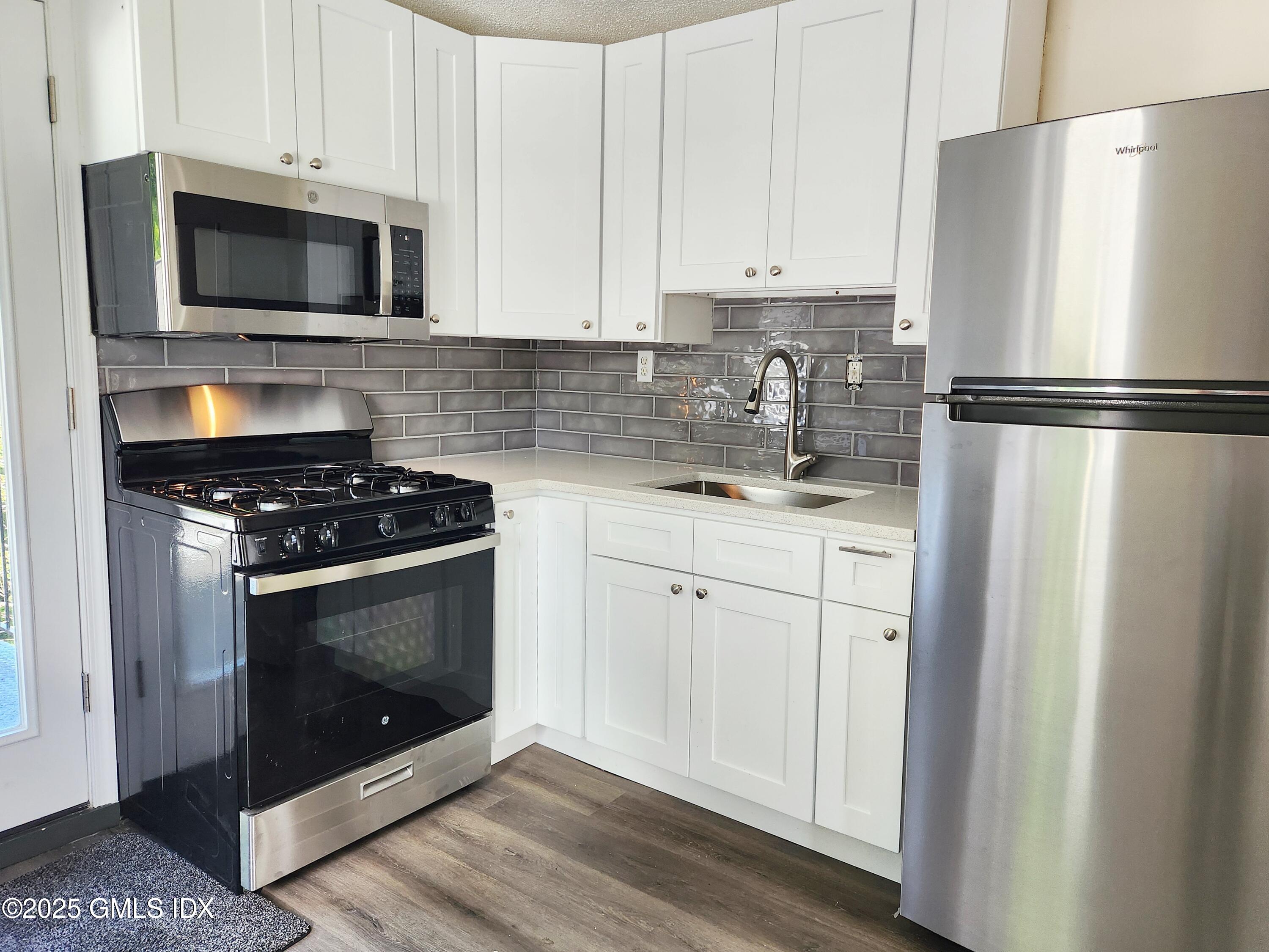 a kitchen with stainless steel appliances white cabinets a stove a microwave and a refrigerator