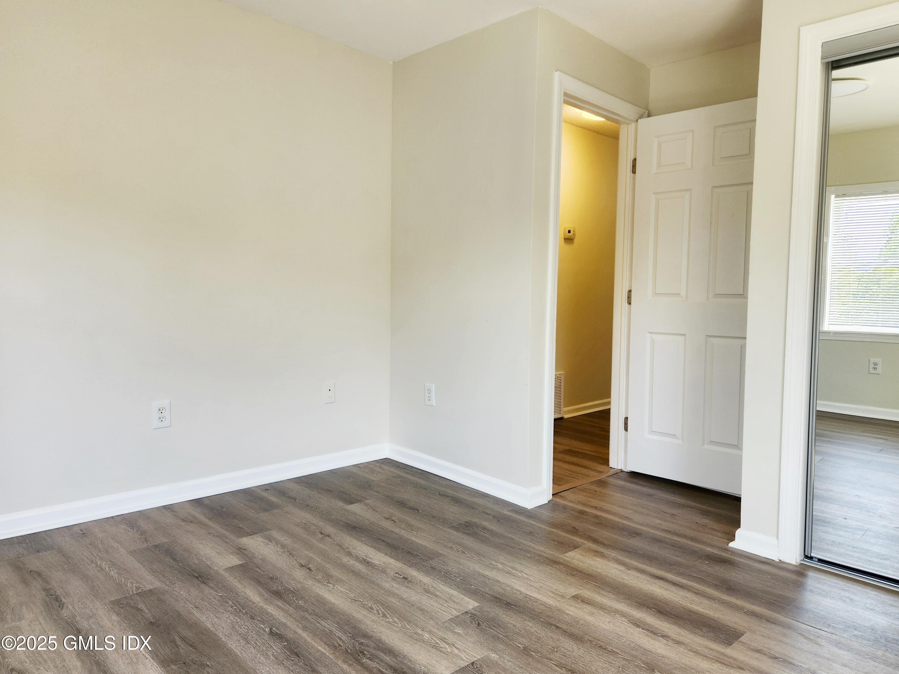 336 Hamilton Avenue, Unit B Greenwich, CT 06830 - Photo 11 of 16 a view of an empty room with wooden floor and a window