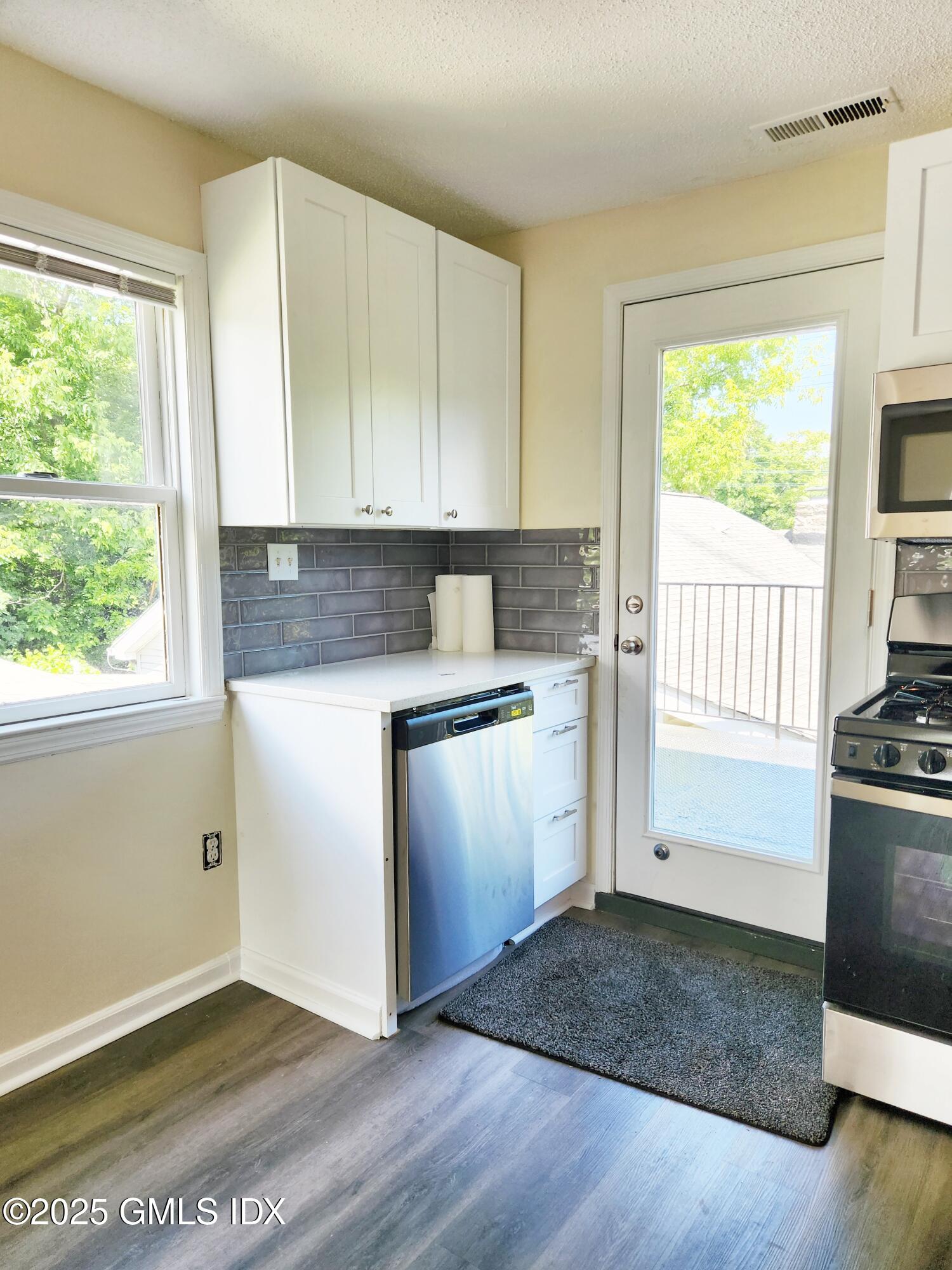 336 Hamilton Avenue, Unit B Greenwich, CT 06830 - Photo 2 of 16 a kitchen with granite countertop wooden floors and wide window