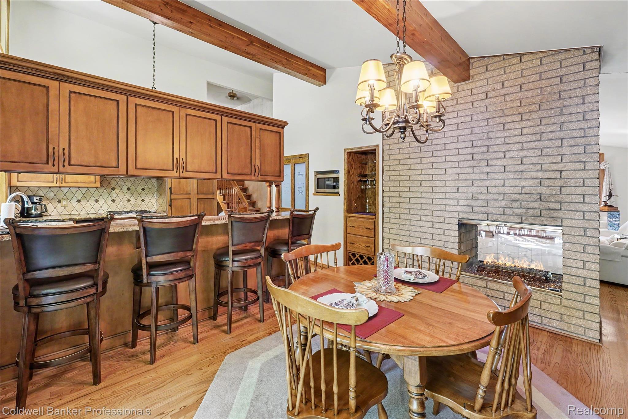 3583 Mitchell Road Metamora, MI 48455 - Photo 17 of 58 Spacious kitchen and dining area with hardwood flooring, exposed wood beams, and a brick fireplace