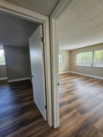 a view of an empty room with wooden floor and window
