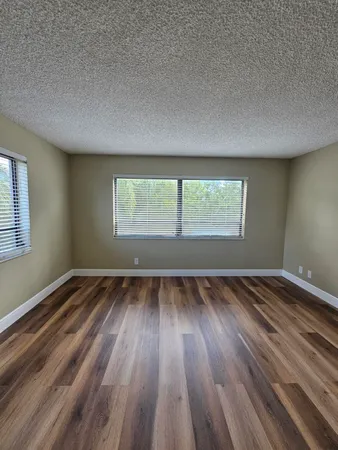 a view of an empty room and wooden floor and window
