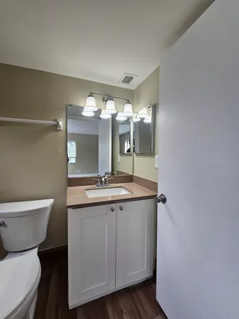 a bathroom with a granite countertop toilet a sink and a mirror