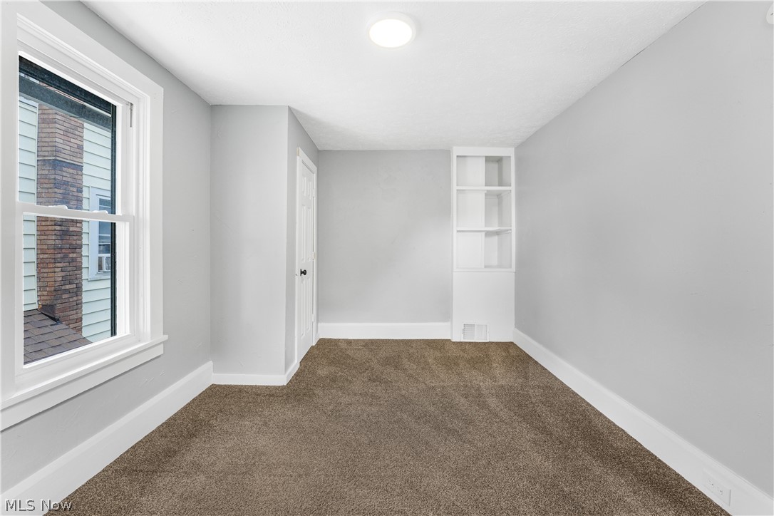885 Wales Road Northeast Massillon, OH 44646 - Photo 18 of 34 Carpeted room featuring light gray walls, white trim, a built-in shelving unit, and a window with white framing