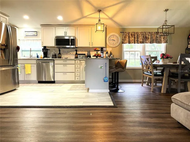 a kitchen with stainless steel appliances wooden floor and refrigerator