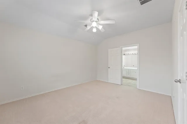 a view of an empty room with chandelier fan