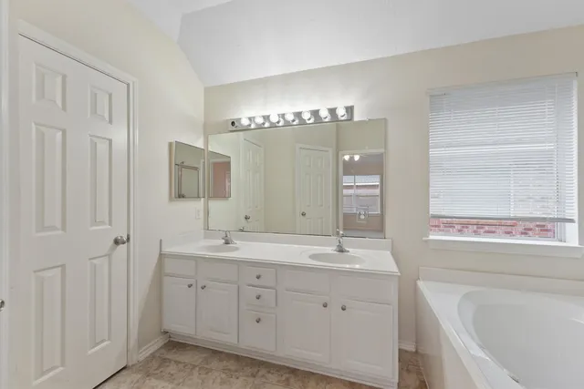a spacious bathroom with a double vanity sink a mirror a bathtub and
