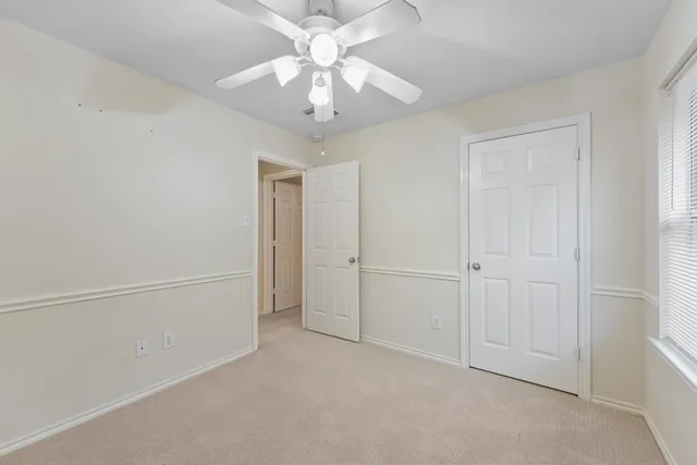 an empty room with a ceiling fan and a window