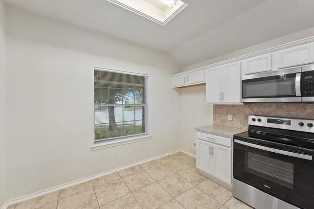 a kitchen with granite countertop a stove top oven and cabinets