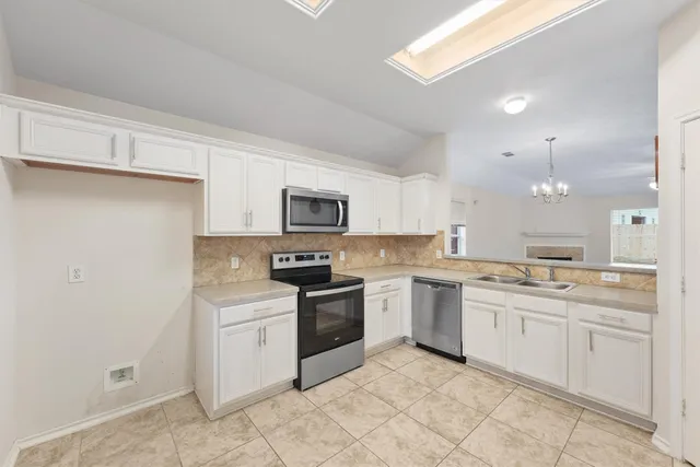a kitchen with a sink white cabinets and white appliances