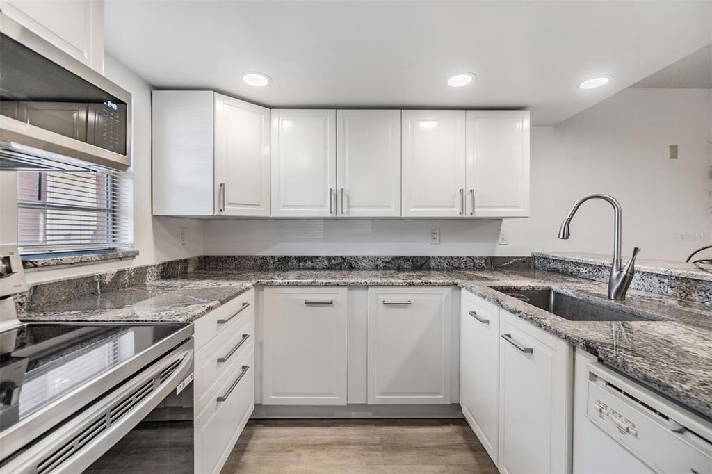 12760 Indian Rocks Road, Unit 104 Largo, FL 33774 - Photo 4 of 37 a kitchen with granite countertop white cabinets and white appliances