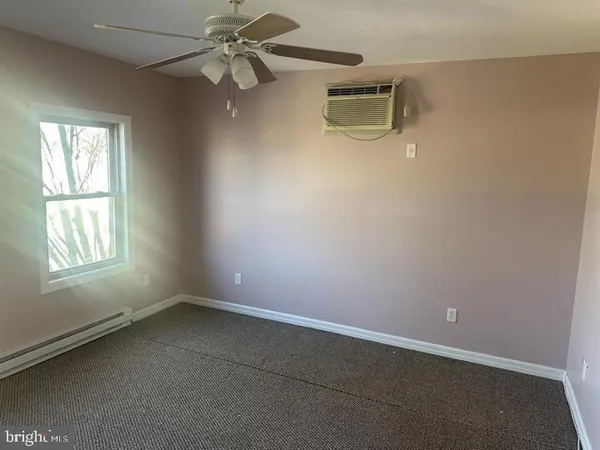 an empty room with a window and ceiling fan