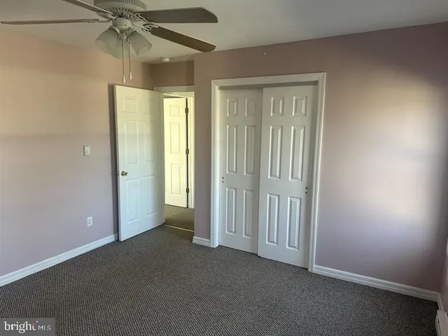 an empty room with closet and a chandelier fan