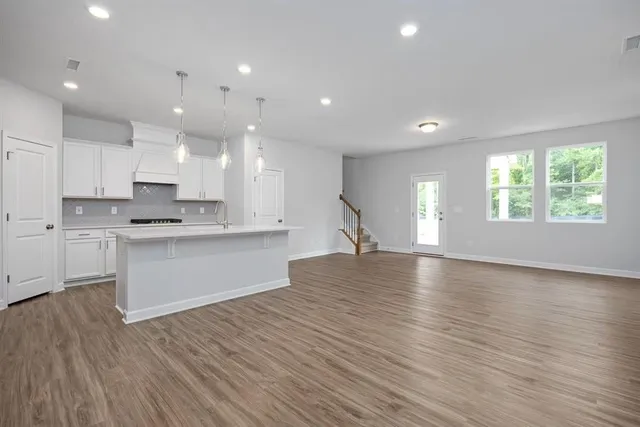 a large kitchen with stainless steel appliances granite countertop a large window a oven and white cabinets