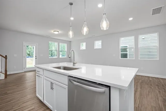 a kitchen with a sink chandelier and wooden floor