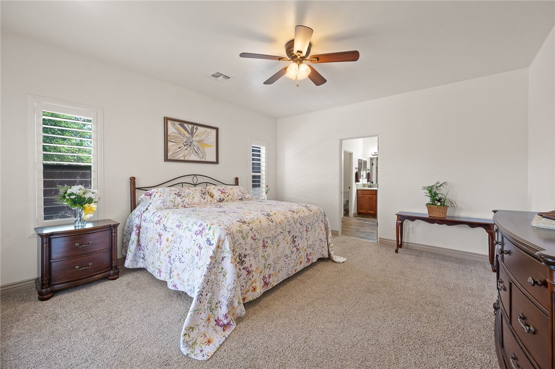 3319 Motherload Road Kingman, AZ 86401 - Photo 14 of 53 Primary bedroom featuring light colored carpet, plantation shutters, a ceiling fan, and a connected primary bathroom