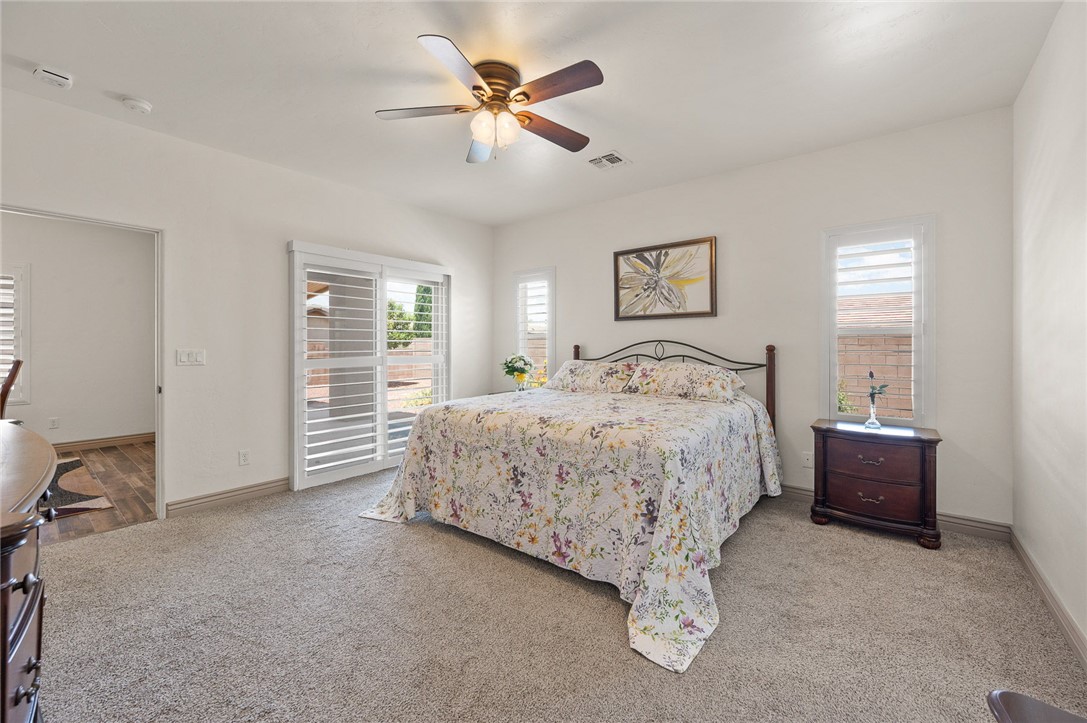 3319 Motherload Road Kingman, AZ 86401 - Photo 15 of 53 Primary bedroom featuring light colored carpet, plantation shutters, a ceiling fan, and sliding glass doors leading to the back covered patio