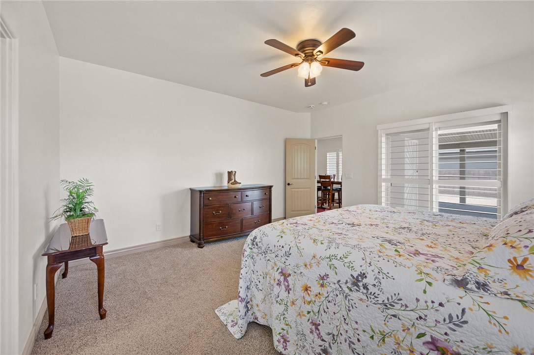 3319 Motherload Road Kingman, AZ 86401 - Photo 16 of 53 Primary bedroom featuring light colored carpet, a ceiling fan, and sliding glass doors leading to the back covered patio