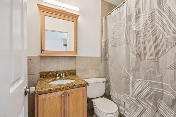 a bathroom with a granite countertop sink and a toilet