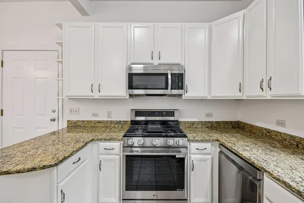 a kitchen with granite countertop white cabinets and a stove a oven with white countertops