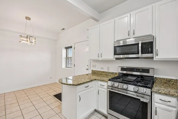 a kitchen with kitchen island granite countertop white cabinets stainless steel appliances and a counter space