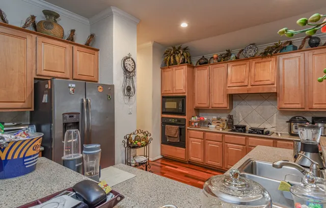 a kitchen with stainless steel appliances granite countertop a refrigerator a sink dishwasher a stove and a dining table with wooden floor