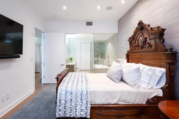 a bedroom with a bed and a flat tv screen on wall