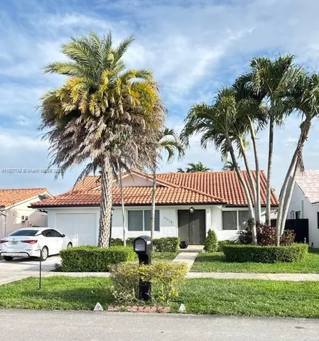a front view of a house with a garden and palm trees