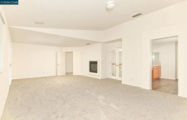 a view of an empty room with wooden floor and stairs