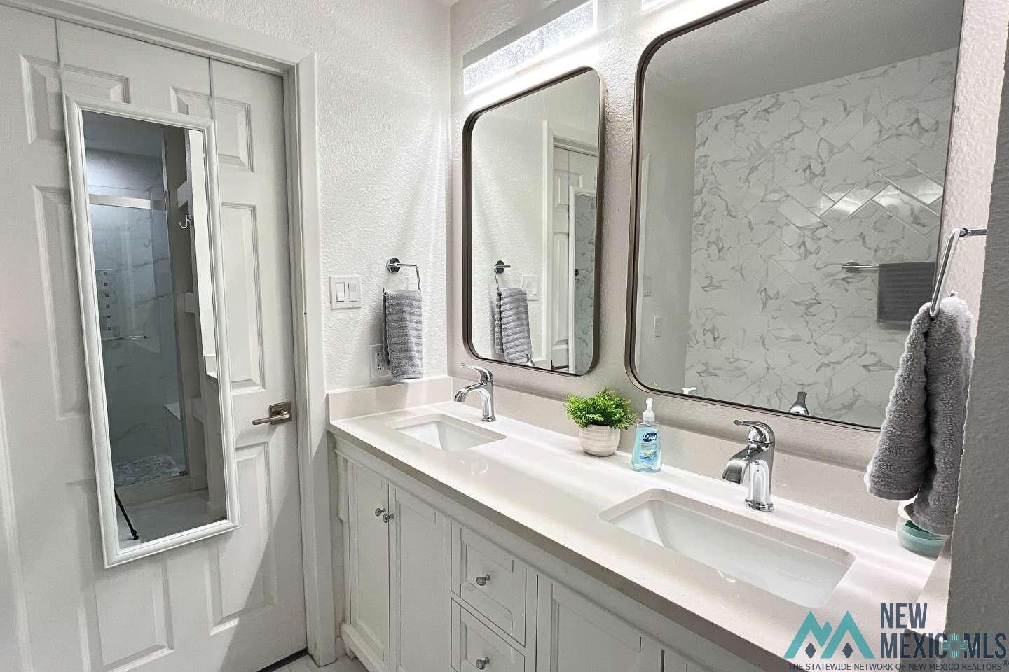 241 Junction Road Ruidoso, NM 88345 - Photo 19 of 44 Full bathroom featuring a textured wall, double vanity, and a stall shower