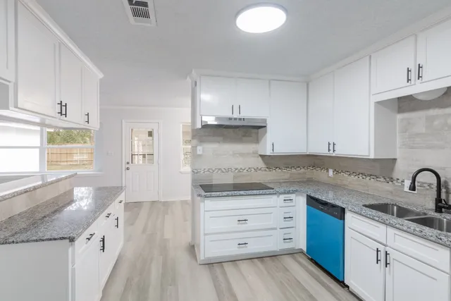 an empty room with wooden floor chandelier fan and windows