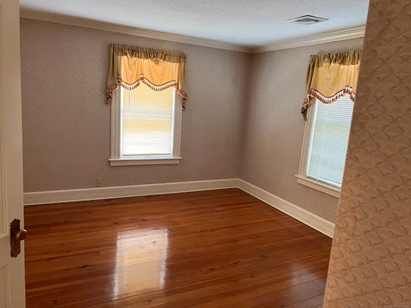a view of empty room with wooden floor and a window