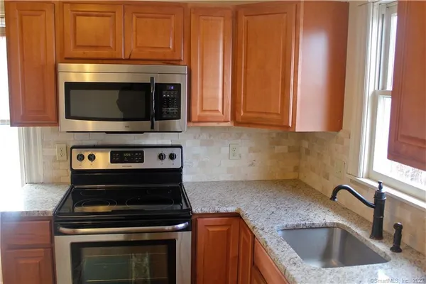 a kitchen with stainless steel appliances granite countertop a sink a stove a microwave and cabinets