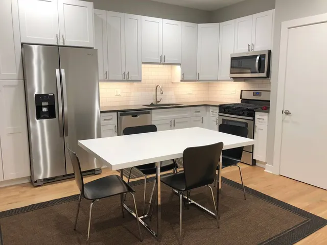 a kitchen with stainless steel appliances a table chairs microwave and refrigerator
