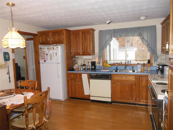 7 Dondi Road Beverly, MA 01915 - Photo 2 of 22 a kitchen with granite countertop a refrigerator a sink dishwasher a stove and a dining table with wooden floor
