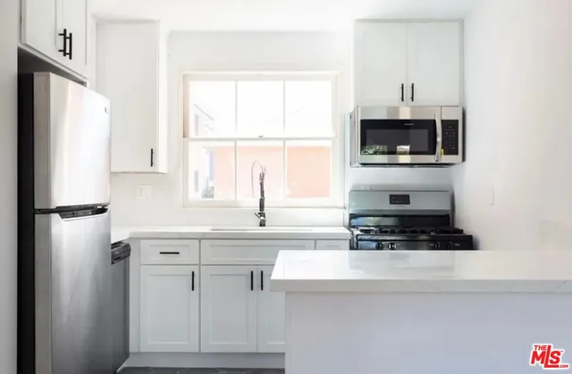 a kitchen with stainless steel appliances a stove a sink a refrigerator a window