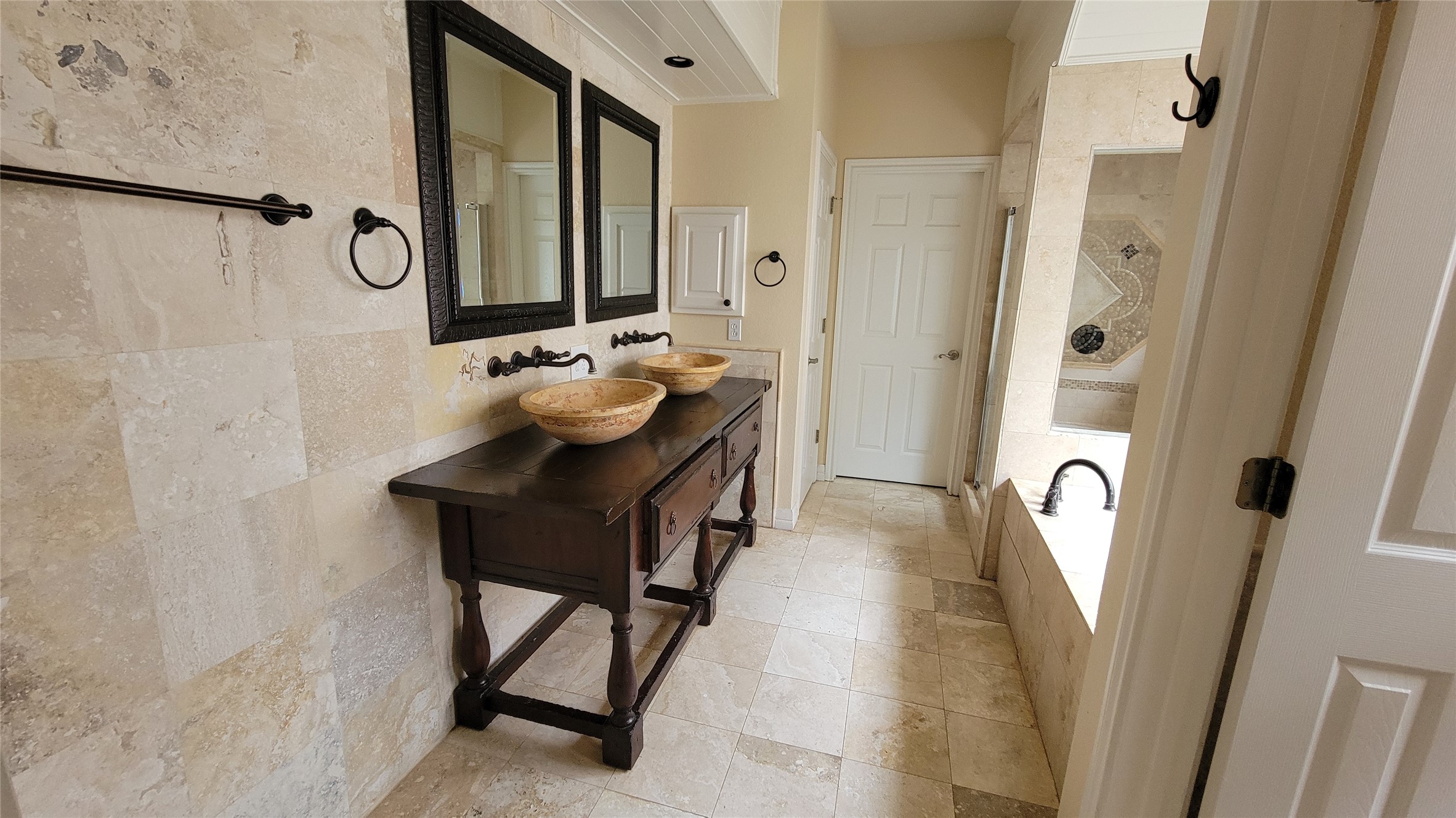 2832 Grimes Ranch Road Austin, TX 78732 - Photo 26 of 37 A lavish bathroom features dual vessel sinks atop a dark wood vanity and a tiled soaking tub.