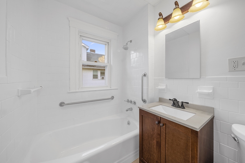 180 Faneuil Street, Unit 2 Boston, MA 02135 - Photo 16 of 37 a bathroom with a bathtub sink vanity and mirror