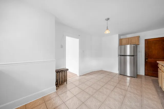 a view of empty room with wooden floor and kitchen