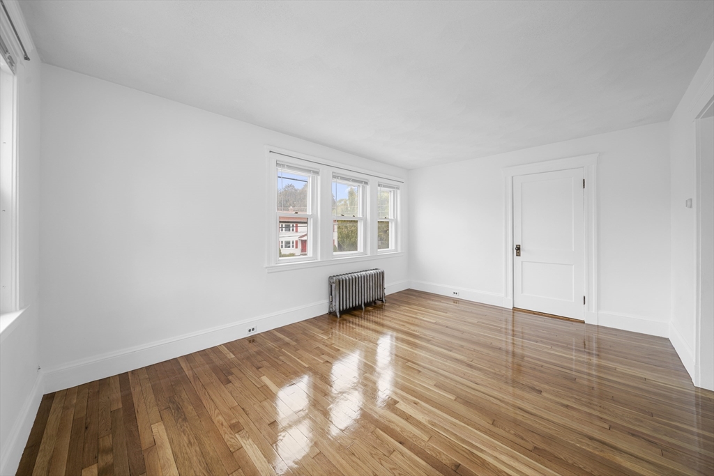 180 Faneuil Street, Unit 2 Boston, MA 02135 - Photo 9 of 37 a view of an empty room with wooden floor and a window