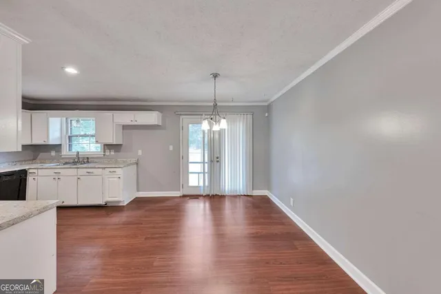 a kitchen with granite countertop a stove a sink and white cabinets with wooden floor