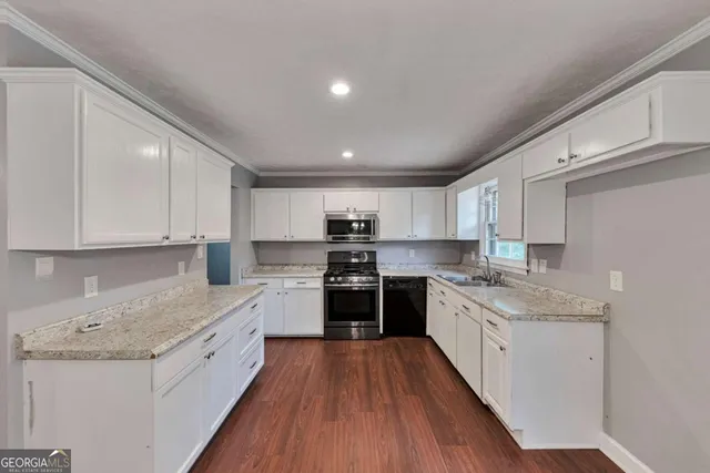 a large kitchen with stainless steel appliances granite countertop a stove top oven a sink dishwasher and a refrigerator with wooden floor