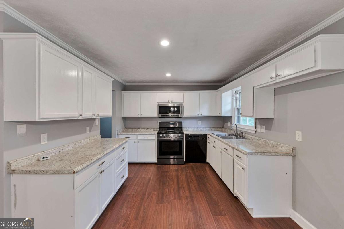 115 Elizabeth Way Ellenwood, GA 30294 - Photo 5 of 15 a large kitchen with stainless steel appliances granite countertop a stove top oven a sink dishwasher and a refrigerator with wooden floor